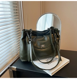 Dettaglio della borsa tote verde scuro con trama in morbida pelle e chiusura a scatto argento
