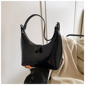 Dettaglio di un'elegante borsa hobo nera lucida con cerniera argentata e manico corto