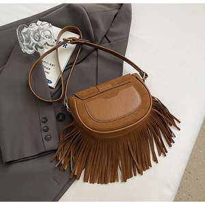 Close-up of brown matte saddle bag with fringe tassels on grey blazer backdrop