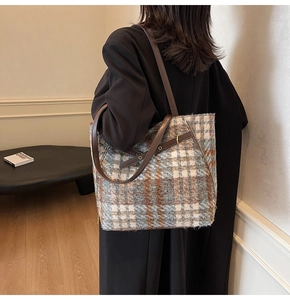 Nahaufnahme der blau-braunen Tweed-Tasche mit Lederriemen und stilvollen Metallösen-Details