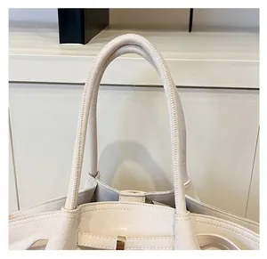 Dettaglio del comodo manico arrotondato e della finitura in pelle scamosciata della borsa