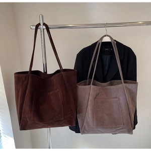 Detail showing high-capacity suede tote bags in dark brown and taupe with outer pockets