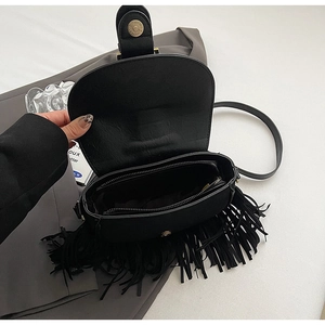 Detail view of black PU leather saddle bag with tassel trim and magnetic flap closure