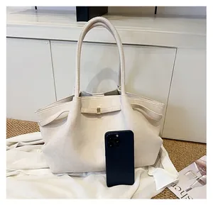 Dettaglio della borsa tote in pelle scamosciata beige con pieghe e fibbia per confronto taglie