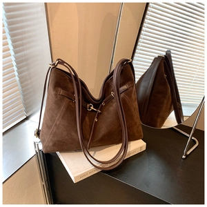 Detail of dark brown suede tote bag with leather straps and metal buckle decoration