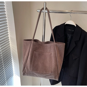 Detail of coffee brown faux suede tote bag featuring a front pocket and long dual straps