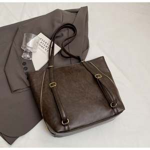 Detailed shot of dark brown vintage tote bag with gold buckle and smooth leather texture