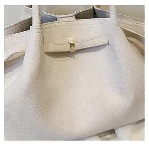 Dettaglio borsa tote in pelle scamosciata beige con manici tondi e fibbia dorata