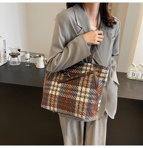 Detail der Vintage-Plaid-Woll-Tragetasche mit dicker Tweed-Textur und Lederriemen-Details