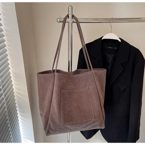 Close-up of large suede tote bag with front pocket and slim straps on display