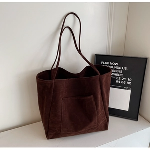 Detailed view of brown faux suede tote bag featuring a front pocket and long handles