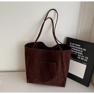 Close-up of a chocolate brown suede tote bag featuring a front pocket and soft matte texture