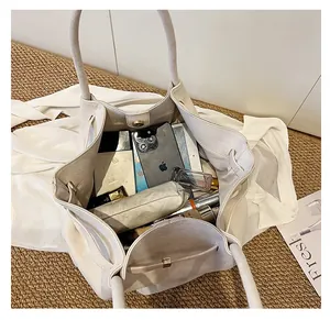 Dettaglio della borsa tote in pelle scamosciata bianca con grande capienza interna utile