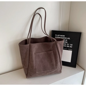 Close-up of suede tote bag with front pocket on white marble surface for a chic look