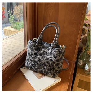 Détail du sac seau en fausse fourrure léopard avec poignées en cuir et boucles dorées
