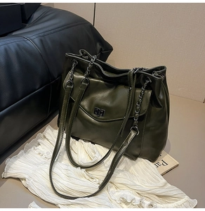 Dettaglio della borsa tote verde scuro con pieghe in pelle opaca e tracolla a catena