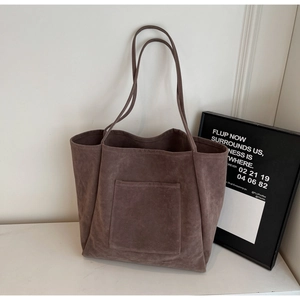 Detail of deep brown suede tote bag with front pocket on marble surface background