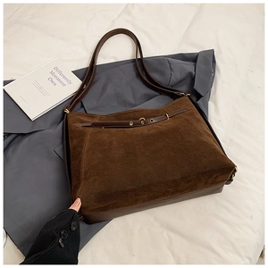 Close-up of large dark brown suede tote bag with leather belt buckle and gold hardware