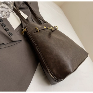 Detail of dark brown vintage leather tote with gold hardware and zipper accents