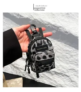 Detailed close-up of leopard print mini bag charm with black zipper and lobster clasp