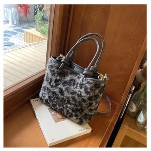 Dettaglio della borsa in peluche leopardata con manici in pelle e fibbia in metallo dorato