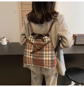 Detailansicht des Tweed-Karo-Rucksacks mit braunen Lederriemen, getragen von einem Model
