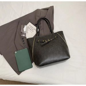 Detail shot of a dark brown vintage PU leather tote bag with stylish gold zipper accents
