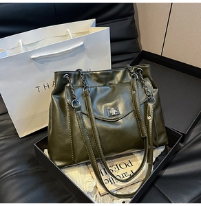 Dettaglio borsa tote in pelle verde oliva scuro con chiusura a scatto e catena in metallo