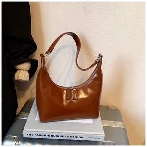 Dettaglio della borsa a mezzaluna marrone vintage in finta pelle lucida con fibbie in metallo