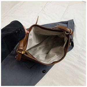 Detail view of brown leather bag interior with light gray lining and secure gold zipper pocket