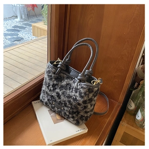 Dettaglio della borsa a secchiello peluche leopardata con manici in pelle e finiture oro