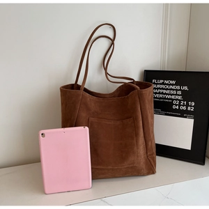 Brown suede tote bag detail showing large capacity compared to a pink tablet device