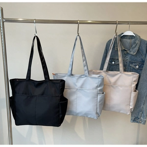 Gros plan de trois sacs fourre-tout à poches multiples en noir, bleu clair et beige clair