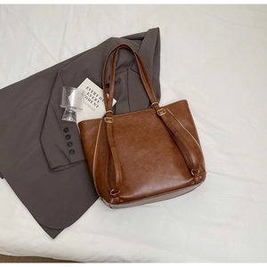 Close-up of vintage brown tote bag with matte PU leather texture and gold zipper detail