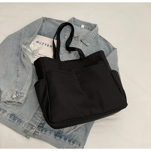 Détail d'un cabas noir en nylon avec poches avant pratiques et bandoulière en tissu
