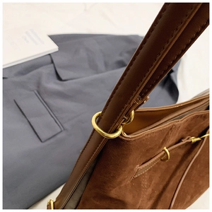 Detailed close-up of brown suede tote bag with leather straps and gold metal ring buckle