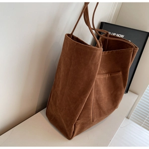 Detailed view of dark brown faux suede tote bag with a side pocket on marble surface