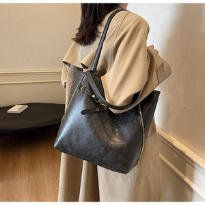 Detail view of large charcoal tote bag with side zipper and decorative buckle strap