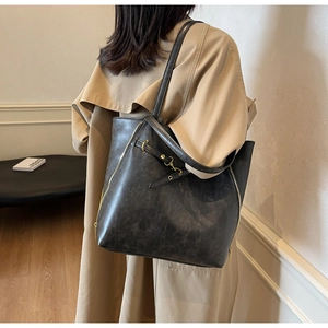 Detail view of large vintage black leather tote with side zippers and buckle hardware