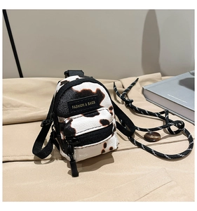 Detail view of mini cow print crossbody bag with fashion label and zipper closure