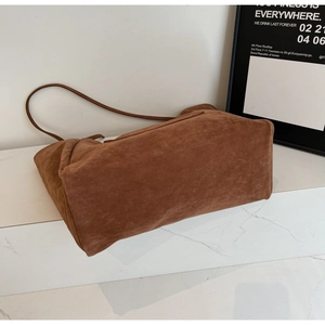 Detail view of large brown suede tote bag with slim shoulder strap and matte texture