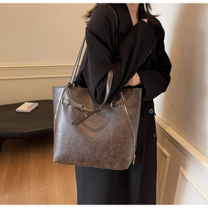 Detail of dark brown vintage faux leather tote with metallic zippers and textured finish