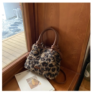 Dettaglio della borsa a secchiello in peluche leopardata con manici in pelle e logo