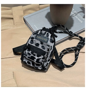 Close-up of mini spotted plush crossbody bag with zipper and woven shoulder strap detail