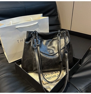 Dettaglio della borsa tote retrò nera con trama in pelle lucida e chiusura a girello in metallo