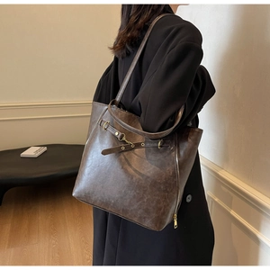 Side view of model wearing a vintage dark brown large tote bag with side zippers