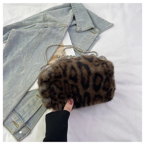 Detail einer Handtasche aus Leoparden-Kunstpelz mit Silberkette vor einer Denim-Jacke
