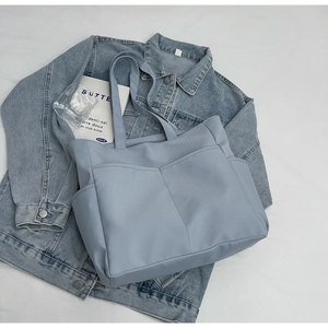 Détail à plat d'un sac cabas bleu clair en toile avec design multi-poches pratique