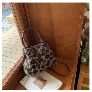 Dettaglio della borsa a secchiello in peluche leopardata su un davanzale in legno