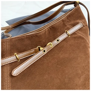 Detail of dark brown suede shoulder bag with leather belt trim and gold metal rings